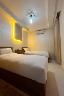 two beds in a hotel room with yellow lights at Appartement cosy à 8 min de RAK à pied in Marrakech