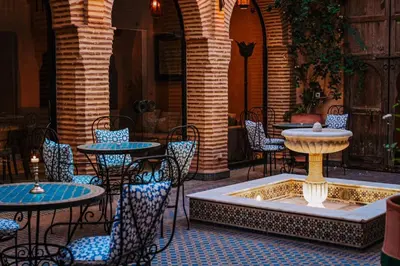 a patio with tables and chairs and a fountain at La Villa Wassim in Marrakech