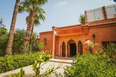 an orange building with palm trees in front of it at La Villa Wassim in Marrakech