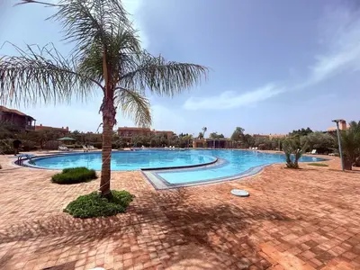 a palm tree sitting next to a swimming pool at Appartement les jardins de la Palmeraie III in Marrakech