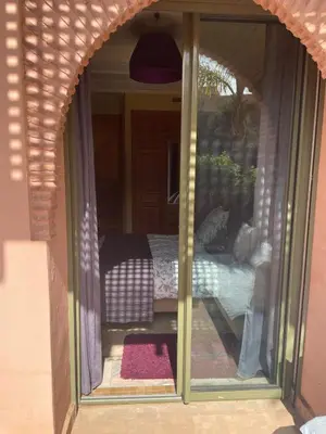 a sliding glass door of a room with a bed at Appartement les jardins de la Palmeraie III in Marrakech