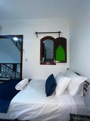 a bedroom with a white bed with a mirror on the wall at Riad Mounaf in Marrakech