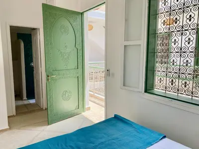 a bedroom with a green door and a window at Riad Nouonsa 4ch 8 pax Medina Bab Taghzout in Marrakech