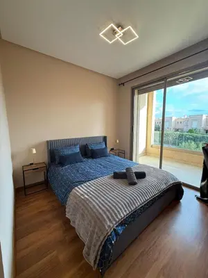 a bedroom with a bed and a large window at Appartement prestigia Marrakech in Marrakech
