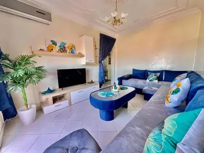 a living room with a blue couch and a tv at NF15 by Majestic Properties in Marrakech