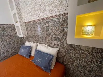 a bedroom with a bed with pillows and a wall at Riad Maaffar in Marrakech