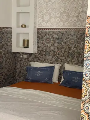 a bedroom with a bed with blue pillows and a mirror at Riad Maaffar in Marrakech