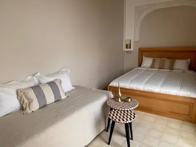 a bedroom with two beds and a side table at Riad Maaffar in Marrakech