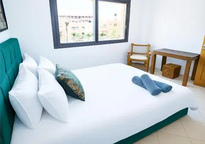 a bedroom with a white bed with pillows and a chair at Appartement moderne Guéliz, Centre Marrakech in Marrakech