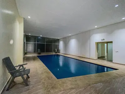 a large swimming pool in a building with a chair at Opera hivernage in Marrakech