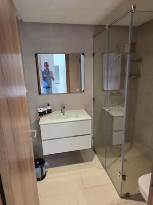 a man taking a picture of a bathroom with a sink and shower at Appartement Résidence Noria Marrakech in Marrakech
