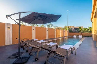 a pool with chairs and an umbrella on a patio at Villa iganis & Spa Marrakech in Marrakech