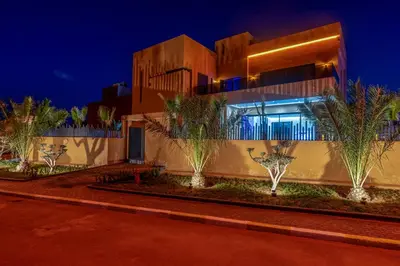 a building with palm trees in front of it at night at Villa iganis & Spa Marrakech in Marrakech