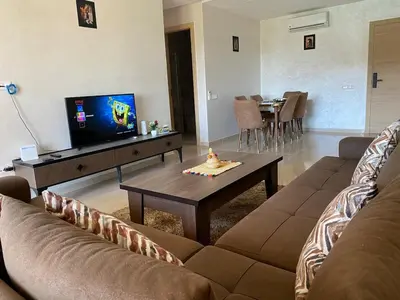 a living room with a couch and a tv and a table at Luxury apartment with 2 pools in Marrakech