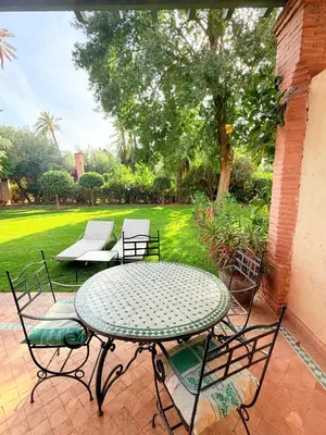 a table and chairs on a patio with a yard at 2 - Bed Apartment with Garden & shared Pool - Moroccan - Modern Style in Marrakech