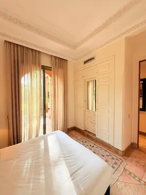 a bedroom with a large white bed in front of a door at 2 - Bed Apartment with Garden & shared Pool - Moroccan - Modern Style in Marrakech