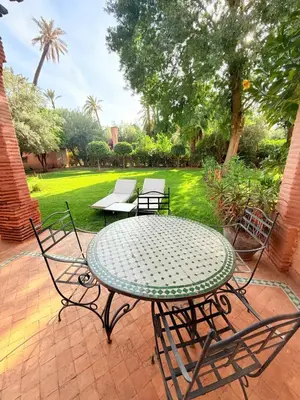 a table and chairs on a patio with a yard at 2 - Bed Apartment with Garden & shared Pool - Moroccan - Modern Style in Marrakech