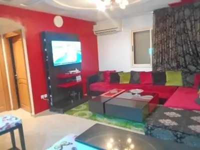 a living room with a red couch and a tv at Appartement Suzette in Marrakech
