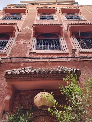a building with three windows and a basket hanging from it at Riad Hostel ADI in Marrakech