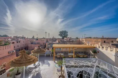 a rooftop patio with umbrellas and a view of a city at Riad du Rabbin in Marrakech