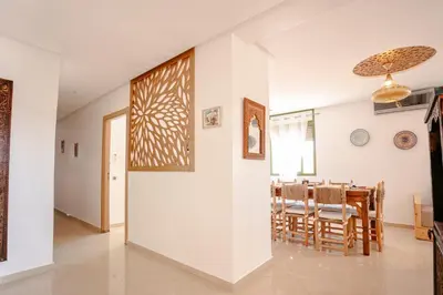 a dining room and living room with a white wall at 6-person appartment, terrace and spa in Marrakech