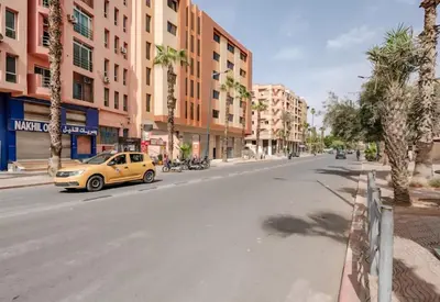 a yellow car driving down a city street with palm trees at Guéliz Marrakech 2,central, spacieux, Authentique in Marrakech