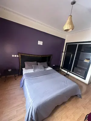 a bedroom with a large bed with a purple wall at apartment in the center of Guéliz in Marrakech