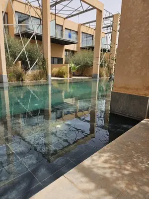 a pool in a building with a reflection in the water at Loft confort, lumineux, avec accès piscine dans une résidence sécurisée in Marrakech