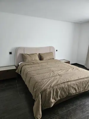a large bed in a bedroom with a white wall at Loft confort, lumineux, avec accès piscine dans une résidence sécurisée in Marrakech