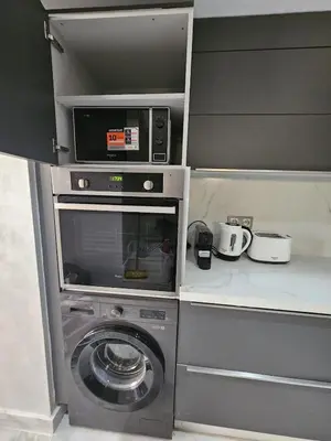 a kitchen with a washing machine and a microwave at Loft confort, lumineux, avec accès piscine dans une résidence sécurisée in Marrakech