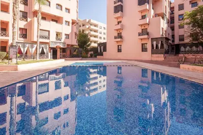 a swimming pool in front of some apartment buildings at Le Berber - Complexe - Piscine - Fitness - Jeux in Marrakech