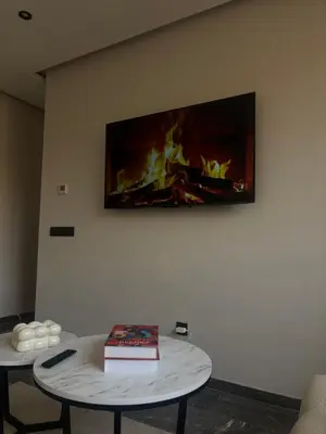 a tv hanging on a wall with a fireplace at Appartement Gueliz Elite garden in Marrakech