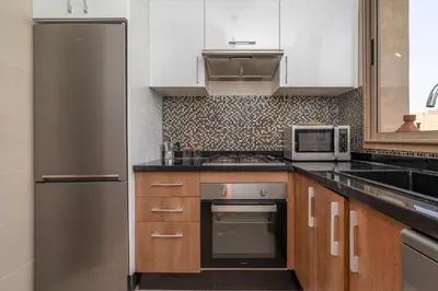 a kitchen with white cabinets and a stainless steel refrigerator at Chic & Cozy Apartment with Pool View - Prestigia in Marrakech