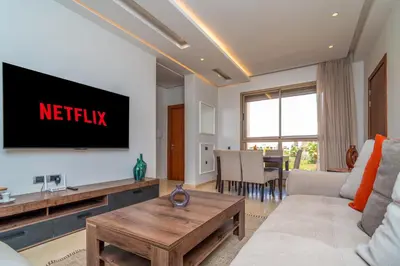 a living room with a couch and a tv on the wall at Chic & Cozy Apartment with Pool View - Prestigia in Marrakech