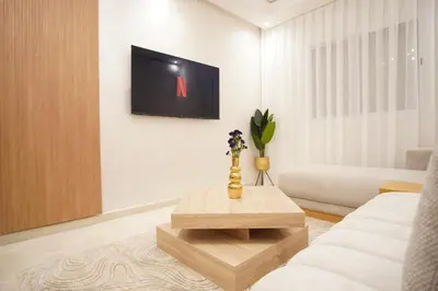 a living room with a couch and a tv on a wall at New cozy 2 bedroom apartment with 3 ACs close to airport and center in Marrakech