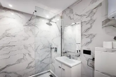 a white bathroom with a shower and a sink at Appartement LA 17 in Marrakech