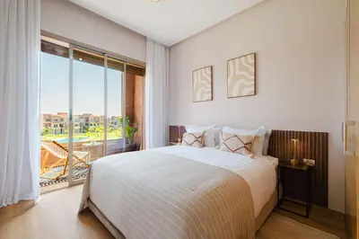 a bedroom with a large bed and a large window at Appartement de charme residence avec piscine WiFi in Marrakech