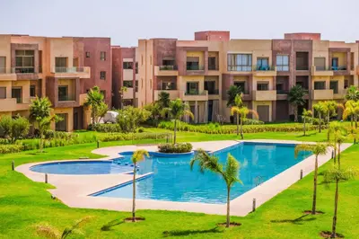 an image of an apartment complex with a swimming pool and palm trees at Appartement de charme residence avec piscine WiFi in Marrakech