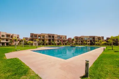 a swimming pool in the middle of a park with buildings at Appartement de charme residence avec piscine WiFi in Marrakech