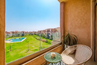 a balcony with a table and chairs and a large window at Appartement de charme residence avec piscine WiFi in Marrakech