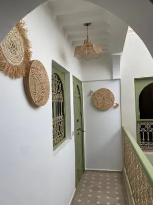 a hallway with white walls and a green door at Riad Médina Bienvenue in Marrakech