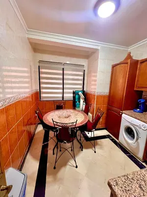 a small kitchen with a table and chairs in it at Élégance & fraîcheur Appart avec piscine in Marrakech