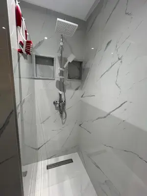 a white bathroom with a shower with marble walls at Élégance & fraîcheur Appart avec piscine in Marrakech