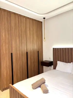 a bedroom with a white bed with a wooden headboard at Magnifique appartement à Guéliz, résidence de luxe in Marrakech