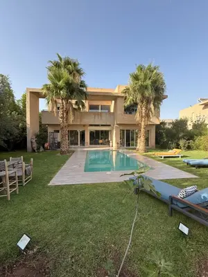 a house with a swimming pool and palm trees at Villa argan in Marrakech