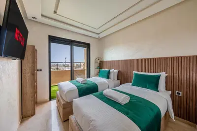 two beds in a room with a flat screen tv at Chic 2BR apartment wifi balcon in Marrakech