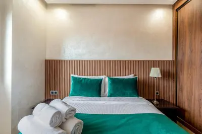 a bedroom with a large bed with green and white sheets at Chic 2BR apartment wifi balcon in Marrakech