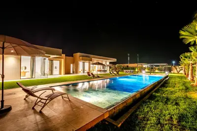 a swimming pool in front of a house at night at Villa Luxe Neuve , Piscine XXL , Sans vis-à-vis in Marrakech