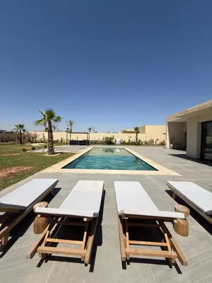 a swimming pool with two picnic tables next to a building at Villa ALIYAH in Marrakech