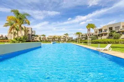 a swimming pool in a resort with palm trees at The Golf Pool Gardens in Marrakech